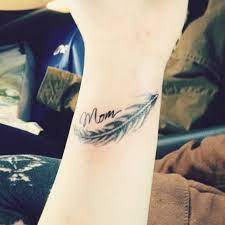 It is a pretty tattoo and the design can be changed so it looks more like you and your child. Wrist Tattoo Saying Mom Together With A Feather On