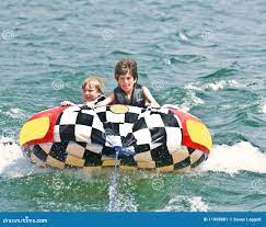 Two Boys on Tube Behind Boat Stock Image - Image of holiday, color: 11908081