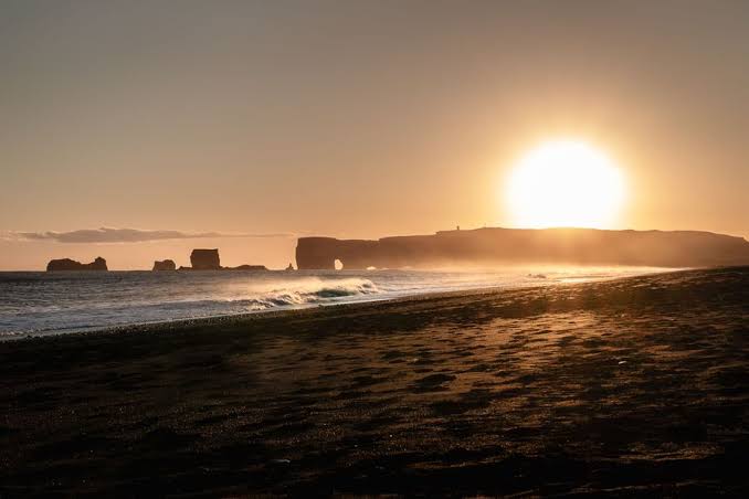 A dark, dramatic landscape in Iceland under a cloudy sky as a total solar eclipse begins to manifest.