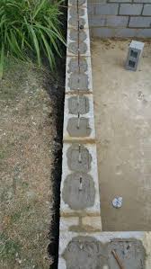 These walls consist of an engineer designed reinforced concrete footing to anchor the wall against overturning and a wall of concrete blocks filled with a concrete grout mix. Concrete Blocks With Reinforced Metal Bars Retaining Walls Concrete Patio Makeover Concrete Retaining Walls Landscaping Retaining Walls