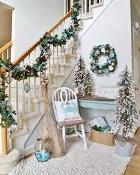 Coastal christmas entryway decor in pale blue, with a garland, a wreath, some trees and ornaments. 25 Warm And Welcoming Christmas Decorated Entryway Ideas