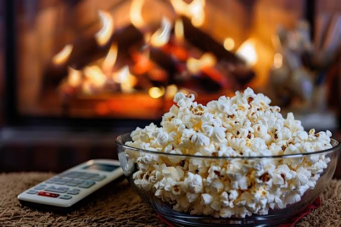 Ilustração de pipoca e controle remoto simbolizando os lançamentos de filmes em agosto nos streamings