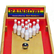 A slender felted wood board shapes the game with ten wooden skittles, a black ball and post, and a cue stick. Rainbowl Alley Tabletop Bowling Home Facebook