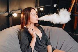 Discover the magic of the internet at imgur, a community powered entertainment destination. Premium Photo Lovely Attractive Girl Exhaling Vapor While Smoking An Electronic Cigarette Spending Leisure Time While Resting On Soft Pouf Sitting In The Design Room