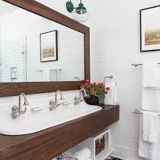 Curved black mirror hangs from a wall clad in gray stacked tiles over a brown inset dual washstand finished with a white quartz countertop and antique brass faucets. Brown Shiplap Bathroom Wall Trim Design Ideas