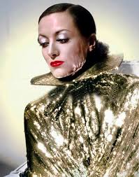 Joan Crawford in Sadie Mckee(1934) wears Adrian-designed evening gown that  bares Joan's shoulders. The sequined halter adds a lot of dazzle to the  long black gown.A shimmering sequin-covered cape completes the outfit.