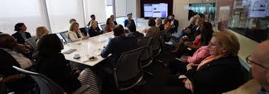 Multidisciplinary team meeting in a conference room with presentation screen, illustrating oncology collaboration