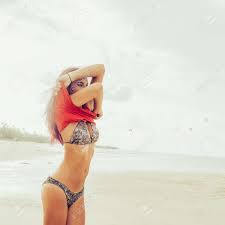 Mujer En Forma En Bikini Sensual En Una Playa Tropical Desnuda Camiseta  Rosa Y Posando Erótica A La Cámara. La Feliz Chica Hipster Moderna Se  Divierte En La Orilla Del Mar. Buen