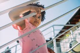 Parents are sure to love that they can get their baby up in the morning and go without a lot of styling. Baby Girl With Curly Hair Standing By Railing On Steps Stockphoto