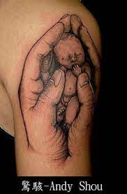 This is one catchy tattoo to get etched with! Baby In Hands Tattoo Design Now This Is Not So Common And Is A Nice Statement Made In Ink Baby Tattoos Hand Tattoos Lost Baby Tattoo