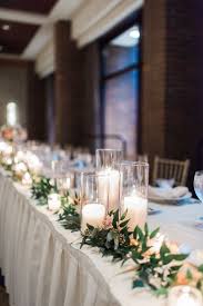 Head Table Decorated With Green Ruscus With A Collection Of Cylinder Candles Head Table Wedding Decorations Bridal Table Decorations Wedding Table Centerpieces