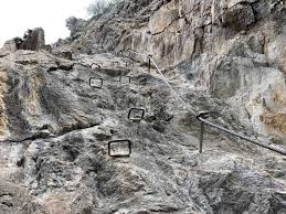 Climbers ascend, traverse, and descend the cliff along the specific path of the cable system. A Mayrhofen Via Ferrata Guide Klettersteig Pfeilspitzwand Zillertal Valley