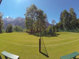 Alpine Grass Tennis Court View Along The Net To The Ski Resort Beyond
