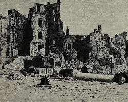 Image of group of mourners stand amidst the ruins of the Warsaw Ghetto after its destruction by the Nazis, 1943