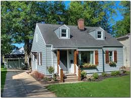 Outdoor living is part of the exterior of this beautiful modern white farmhouse. Bungalow Renovation With Gray Siding Wood Board And Batten Shutters Portico And Window Boxes House Exterior Blue House Exterior House Shutters