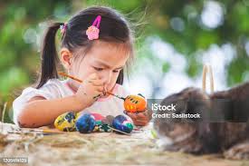 Cute Asian Child Girl Drawing And Painting On Easter Eggs Prepare For Easter  Day Child And Holland Lop Rabbit In Easter Festive Stock Photo