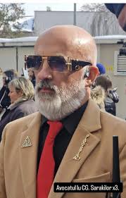 Can someone please tell me who the man is that sits right behind Alex in  court with the beard and suit? Also I don't know why but it drives me crazy  how