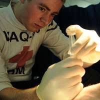 Senior Chief Hospital Corpsman Thomas Gilham, assigned to Commander Task  Force 73 in Singapore, watches Royal Cambodian Armed Forces doctors remove  a cataract from a local woman's eye.
