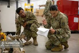 1st Lt. Andrea Viveros and Staff Sgt. Luz Arguello, Headquarters and  Headquarters Company, 11th Signal Brigade, verify sorted boots while  volunteering May 12, 2022, at Fort Hood, Texas, in preparation for the