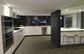 This mid century kitchen shows a smart mix of white quartz and wood in the kitchen island. Modern Black And White Kitchen