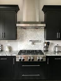 Black worktop, range hood, and refrigerator meet the white units in stunning contrast. Espresso Cabinets With Light Grey Subway Backsplash Herringbone Backsplash With Espresso Kitchen Cabinets Brown Kitchen Cabinets Dark Brown Kitchen Cabinets