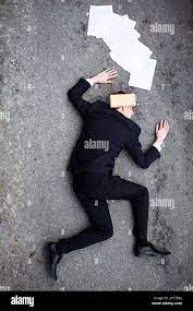 The business world is ruthless. A young man lying dead on the ground with a  brick on his head Stock Photo - Alamy