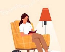 person reading a book in a cozy armchair resmi