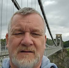 I stumbled upon this  https://www.flickr.com/photos/156515782@N02/52995272769/. The image is not  genuine in respect of the MPs and running-in board but the station is. The  question is where is it? The track uses flat