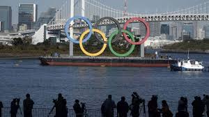 The colors of the rings are green, black, yellow, red, and blue set against the white background of the flag. Giant Olympic Rings Returns To Tokyo Bay Other News India Tv