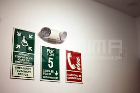 Señal de advertencia para sismos y salida de emergencia fotoluminiscente en un edificio de oficinas en Lima.