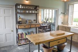 This kitchen simple but elegant kitchen features a handful of industrial finishes, from the exposed pipework and chrome extractor fan, to the exposed brick wall and pendant lights. French Skip Chic Bespoke Kitchen Furniture