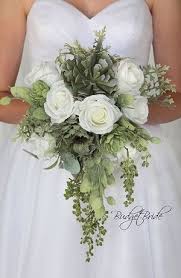 A chic cascading greenery wedding bouquet with a large air plant on top to stand out. Cascading Brides Bouquet With Succulents Lots Of Greenery Silver Dollar Eucalyptus Lambs Bride Bouquets White Succulent Bouquet Wedding Green Wedding Bouquet