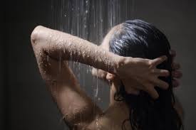 Young beautiful woman taking shower in ...