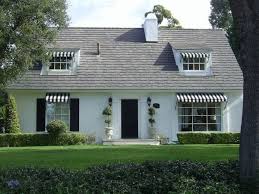 Black And White House Exterior Ideas White Cottage Home With Black And White Awnings Boxwood Hedges And Topiaries Flanking The Fron White House Black Shutters House Exterior White Exterior Houses