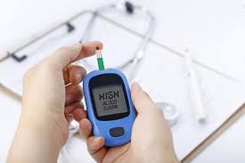 hand holding a blood glucose meter measuring blood sugar