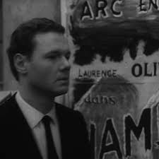 Yvan (André Jocelyn) walking past a poster advertising Laurence...