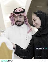 زوجان عربيان خليجيان سعوديان سعيدان بالتسوق معا في المتجر ، زوجة سعودية  تختار ملابس جديدة مع زوجها في متجر الملابس ، الاستمتاع بالشراء والتسوق ،  الاستفادة من العروض والخصومات ، قضاء وقت