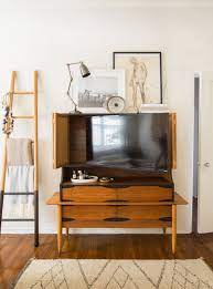 Bowery hill holliday 56 corner tv stand console solid wood with glass door storage in burnished oak. 13 Clever Hidden Tv Ideas How To Hide A Tv According To Top Designers