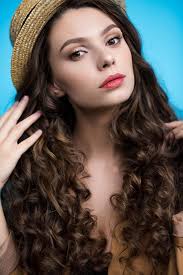 Have you been looking into wearing a longer lasting hair style? Close Up Portrait Of Sensual Young Woman With Long Curly Hair In Canotier Hat Looking At Camera Free Stock Photo And Image
