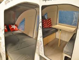Ein Weisses Fahrrad Wohnwagen Mit Einem Kleinen Tisch Aus Holz Und Einem Bett Mit Drei Roten Kissen Bicycle Camping Bike Camping Bed