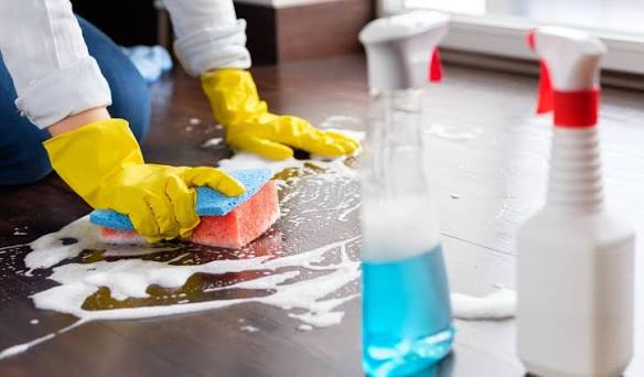 A close-up of non-toxic, eco-friendly cleaning products and a microfiber cloth sitting on a freshly wiped marble kitchen countertop.