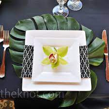 A classy place setting with a lace doily under the cream napkins, which are finished with a white rose and a silky peach ribbon. Square Plates And Black And White Napkins Gave The Tables A Mod Look The Leaf Placem Modern Place Setting Square Plates Table Setting Flower Table Decorations