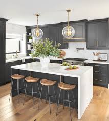Black double wall oven is inserted into the dark wood cabinetry in this kitchen with white subway tile backsplash and white upper cabinets that create balance to the layout. The Top 6 Things Every Well Designed Kitchen Needs