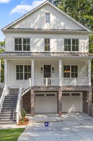 Angled view of the house with white siding, decorative columns, and a brick chimney that reflects the column bases and staircase. 2 Story Off White Modern Farmhouse Home Exterior House Exterior Modern Farmhouse Exterior Modern Farmhouse