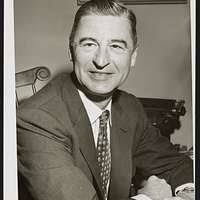 Ted Geisel (Dr. Seuss) half-length portrait, seated at desk covered with  his books]