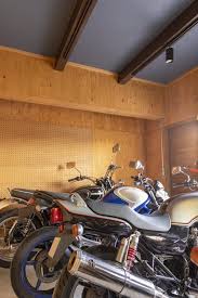 バイクガレージの壁は 釘を打ったり工具をかけたりできるように 合板 有孔ボードで仕上ました バイクを照らすスポットライトや ファクトリーテイストのスイッチにもこだわっています ガレージの壁 ガレージ ガレージハウス