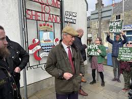 Nigel Farage's visit to Lerwick harbour was met by protesters this morning,  including representatives from the Scottish Green Party. Campaigning  alongside the party's local candidate, the Reform UK leader said expanding  the