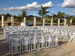 Ceremony Set Up Of White Resin Folding Chairs With A Padded Seat And An Ivory Sash Tied In A Bow Beach Wedding Centerpieces Flowers Chair Sashes Wedding Chairs