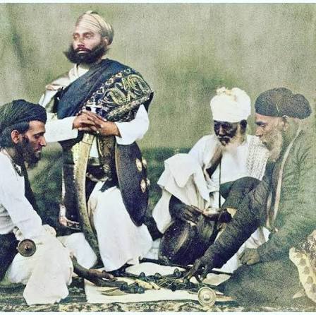 Rajput men playing the game of Puchesee - 1860s A print by Eugene Clutterbuck Impey in the early 1860s showing a group of men from Rajasthan in northern India playing pachisi. This