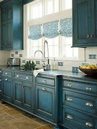 Amazing kitchen boasts a row of distressed gray cabinets adorned with ladder rail suspended over distressed lower cabinets paired with gray marble countertops flanking a wolf range under a white plaster kitchen hood and swing arm pot filler mounted on a white and gray herringbone cooktop backsplash with windows on either side dressed in bamboo roller shades atop wood herringbone pattern floor. Teal Distressed Kitchen Cabinets Kitchen Design Home Kitchens Kitchen Cabinets